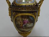 a golden vase with a painting on it on a table