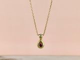 a gold necklace with a tear shaped ruby stone on a gold chain