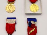 Plusieurs médailles sont exposées dans une boîte blanche posée sur une table