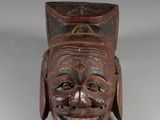 a close up of a wooden mask on a white surface
