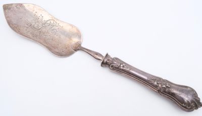 silver plated serving spoon with ornate handle on a white surface