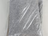 grey t - shirt wrapped in plastic on a white surface