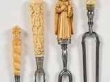 quatre fourchettes ornées de figures sculptées sont alignées sur un fond blanc