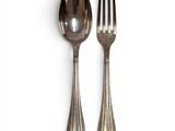 two silver spoons and a fork on a white surface