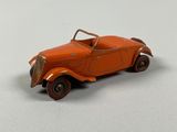 an orange toy car sitting on top of a table next to a white wall