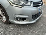 the front end of a silver car with a damaged bumper
