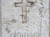 une plaque de pierre sur laquelle est gravée une croix et le mot « Jésus »