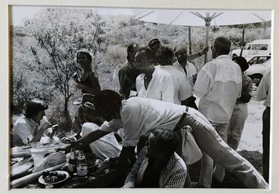 une photo en noir et blanc montrant un groupe de personnes réunies autour d'une table