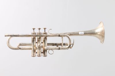 an old silver trumpet hanging from a string on a wall