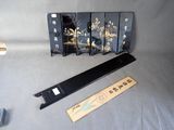 un paravent oriental noir et doré et une règle posés sur une table