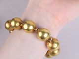 gold plated bracelet with gold balls on a woman ' s wrist