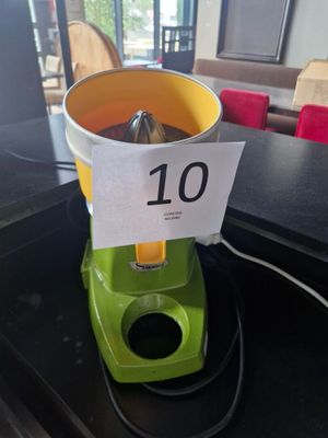 a green blender sitting on a counter with a sign on it