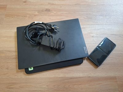 a black laptop and a cell phone on a wooden floor