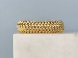 un gros plan d'un bracelet en or posé sur un bloc de marbre