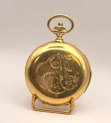une montre de poche en or posée sur un socle, sur fond blanc
