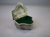 a small silver box with a green lid on a table