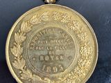 une vieille médaille en or entourée d'une couronne, posée sur un fond noir