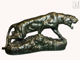 bronze statue of a lion on a rock with its mouth open