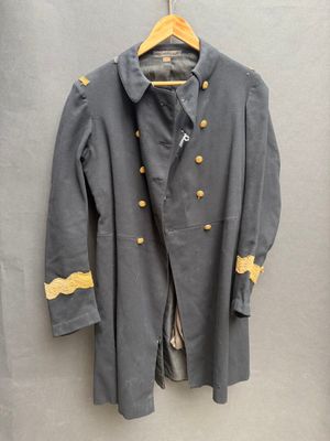 un manteau gris avec des boutons jaunes, suspendu à un cintre accroché au mur