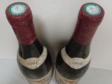 two bottles of red wine sitting on top of a white table