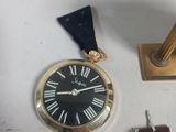 a gold clock with roman numerals and a black leather strap