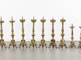 several brass candles are lined up in a row on the floor
