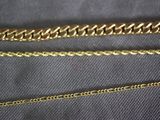 a close up of two gold chains on a black cloth