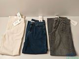three pairs of men ' s jeans are lined up on a table