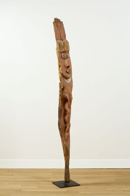 une sculpture en bois dans une pièce aux murs blancs et au sol en bois
