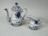 two blue and white teapots and a creamer on a table