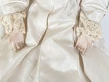 an antique doll with red hair and white dress sitting on a white surface
