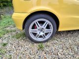 a yellow car that is parked in the gravel