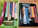 de nombreux livres dans une boîte verte posée sur un plancher en bois