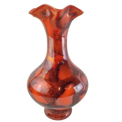 un vase rouge posé sur une surface blanche