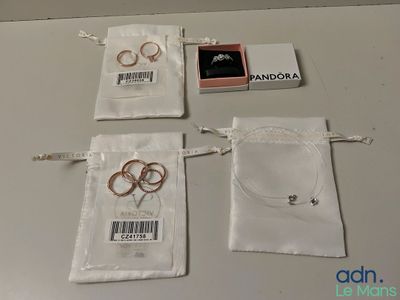 trois alliances sont posées sur un sac en tissu blanc, à côté d'une bague rose