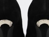 a close up of a pair of black high heels with a silver ring on the heel