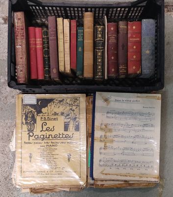 un panier rempli de livres posé par terre à côté d'une bibliothèque