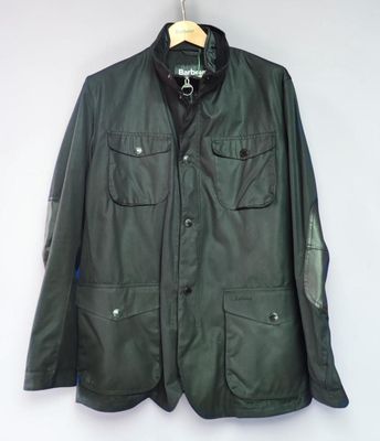 a green leather jacket hanging on a hanger on a wall