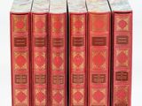 six livres rouges sont alignés sur une surface blanche