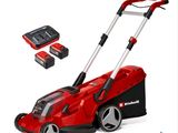 a red corded lawn mower with two batteries and a charger