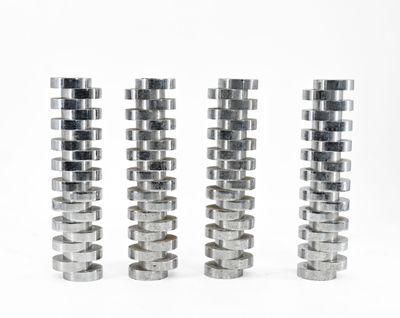 trois piles d'objets métalliques argentés posés sur une surface blanche