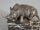 statue of a rhino laying down on a marble base