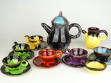 tout un assortiment de tasses et soucoupes de différentes couleurs, ainsi qu'une théière