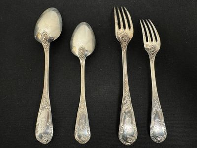 three silver spoons and two silver forks on a black surface