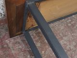 un banc en bois avec une structure métallique posé sur un sol en briques