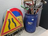 une poubelle et un panneau posé par terre à côté de la poubelle