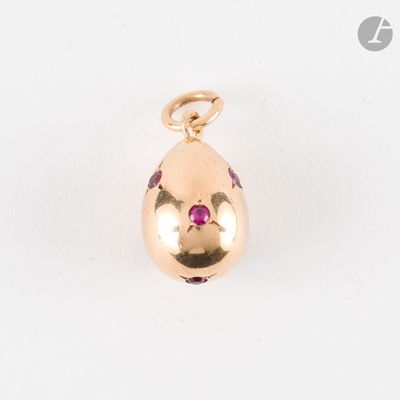 un pendentif en forme d'œuf doré orné de pierres roses sur fond blanc