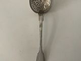 a silver spoon with a flower design on it sitting on a white surface