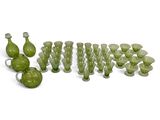 de nombreux vases en verre vert posés sur une surface blanche