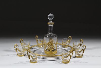 un plateau en verre et en or sur lequel est posé une carafe en verre